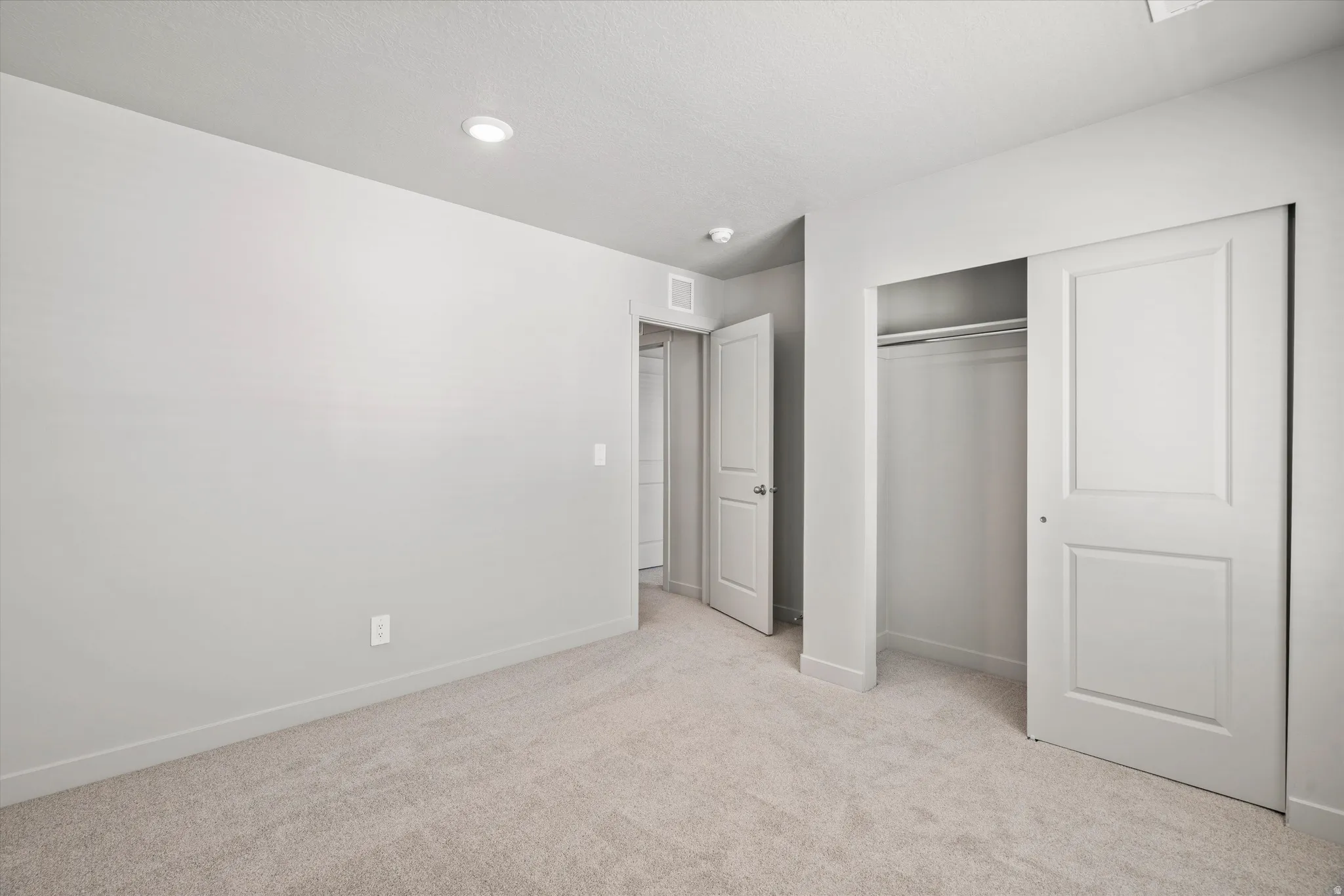 Carpeted room featuring light gray walls, white baseboards, and an integrated ceiling light