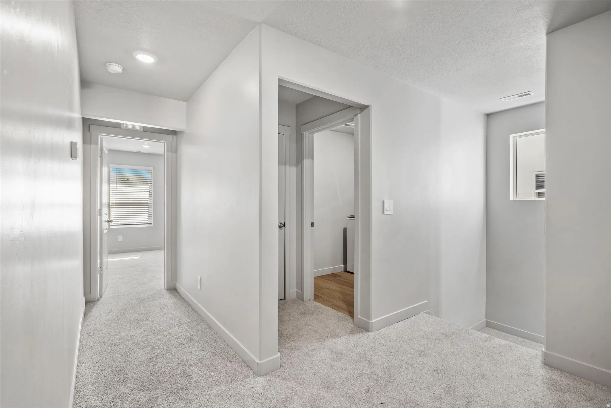 Hallway with light gray carpeting, recessed lighting, and white baseboards