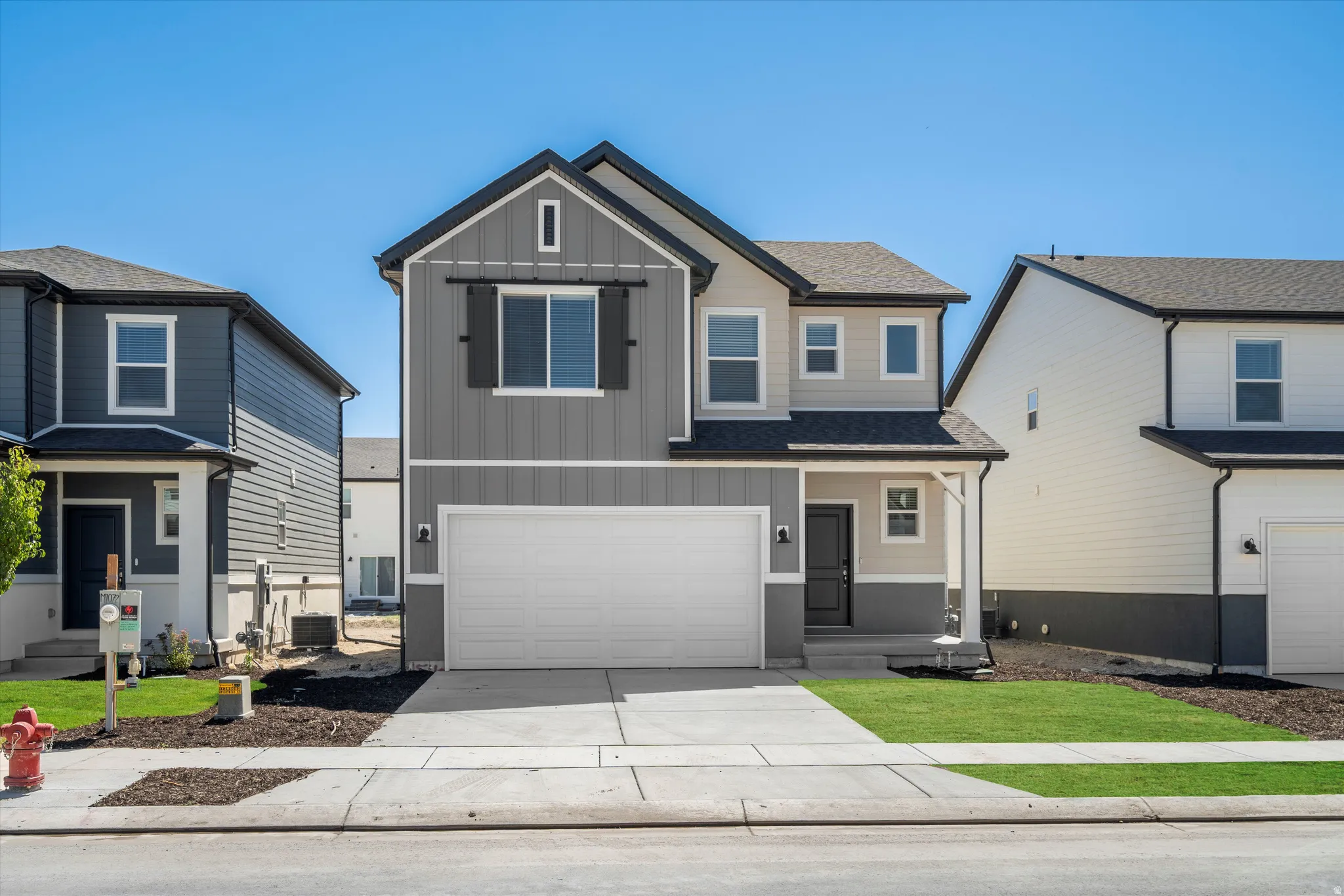 Contemporary two-story residence featuring a two-car garage, covered entry porch, and a combination of vertical and horizontal siding