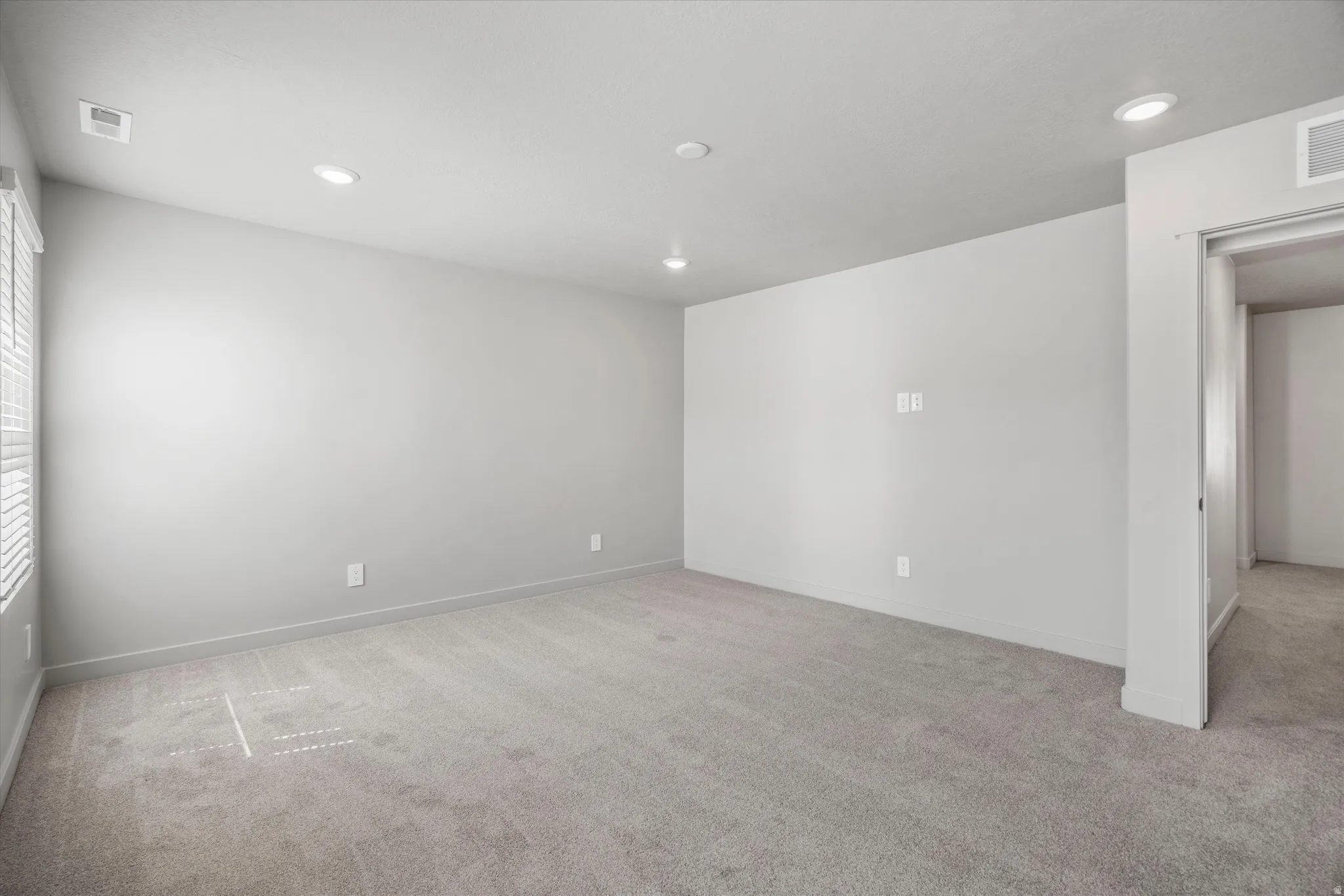 Spacious room with light gray carpeting and neutral wall tones