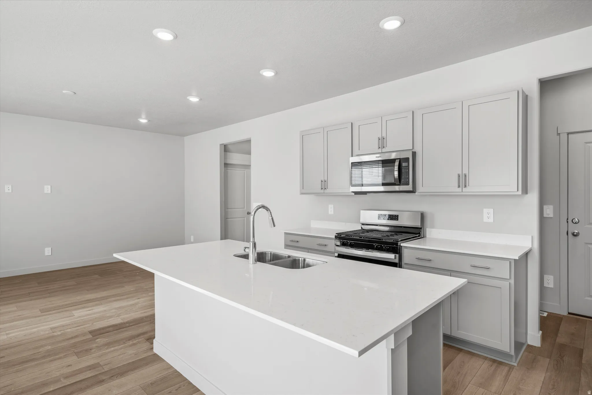 Kitchen with light gray cabinetry, stainless steel appliances, and white countertops