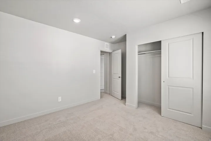 Carpeted room featuring light gray walls, white baseboards, and an integrated ceiling light