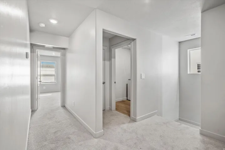 Hallway with light gray carpeting, recessed lighting, and white baseboards