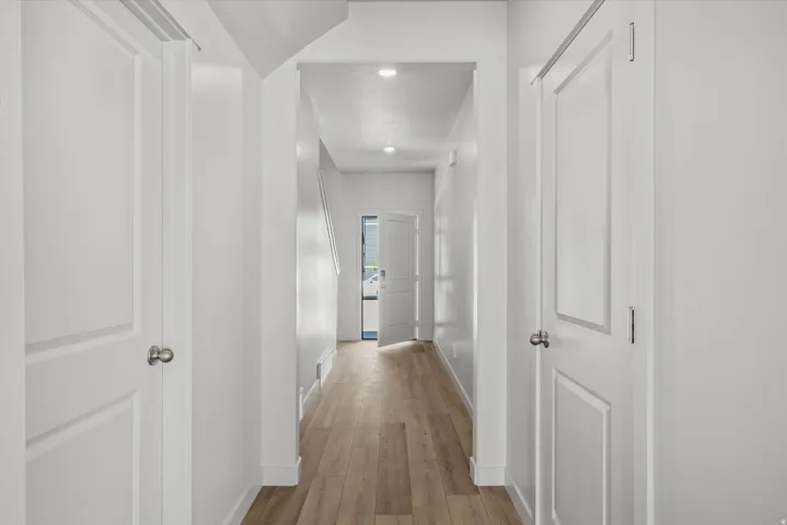 Bright entryway featuring light wood-finish flooring, white walls, recessed ceiling lighting, and panel doors with brushed nickel hardware