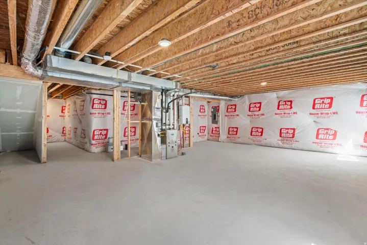Unfinished basement featuring exposed wood joists, concrete flooring, and an HVAC system