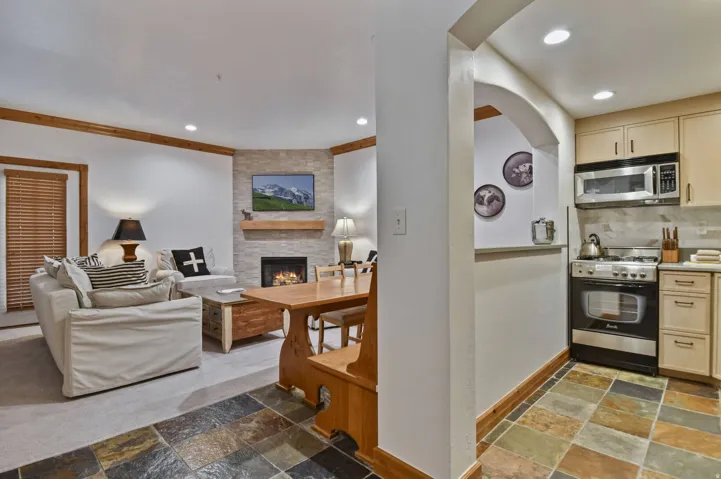 Living area featuring a stone-clad fireplace with a wood mantel, exposed wood ceiling beams, and recessed lighting