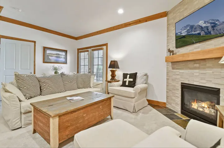 Living area featuring a floor-to-ceiling stone-faced fireplace with a natural wood mantel and hearth