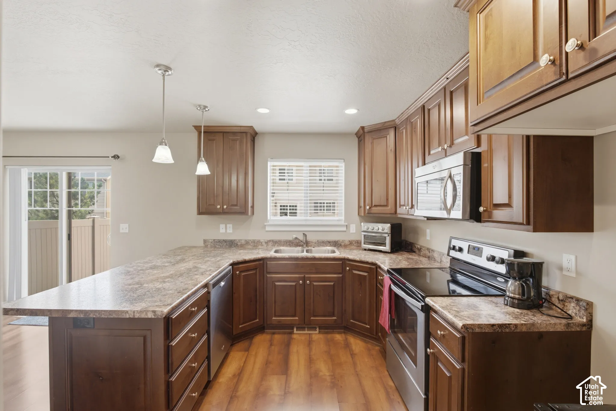 Kitchen featuring extensive U-shaped countertops, wood-finish flooring, and ample cabinetry