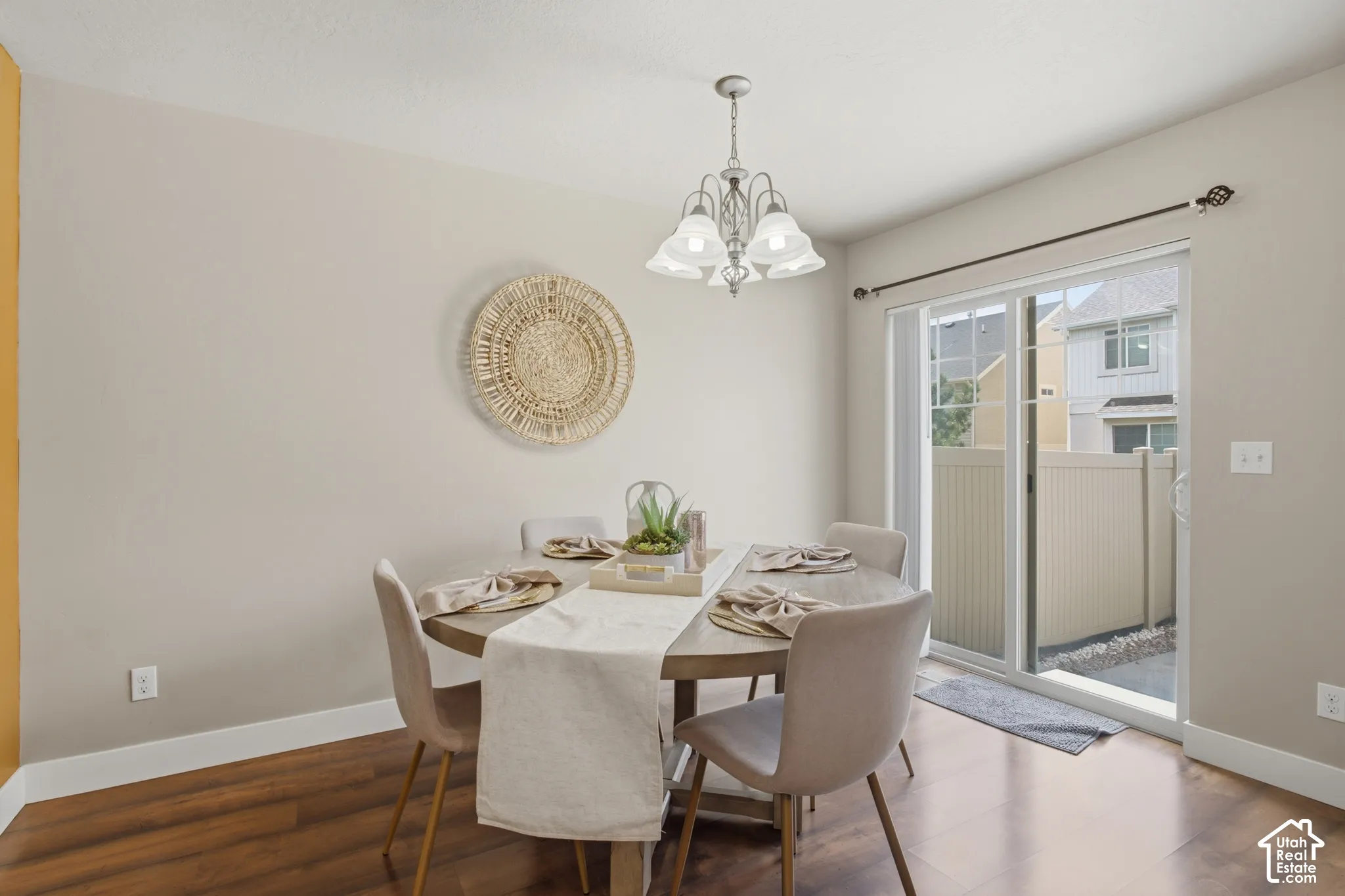 Dining area featuring wood-finish flooring, a contemporary chandelier, and a sliding glass door opening to a private outdoor space