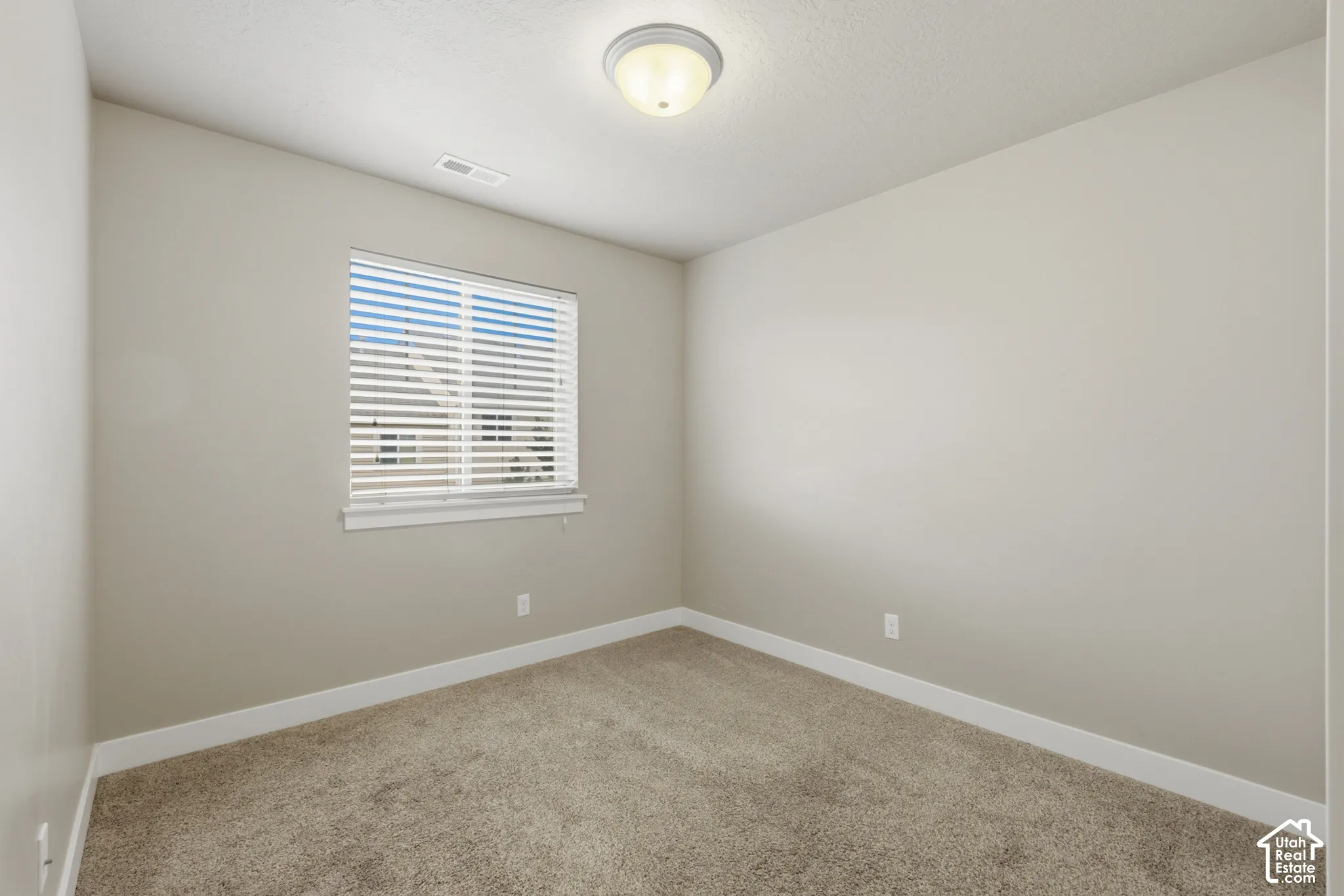 Room featuring neutral-toned walls, white trim, and a window with blinds