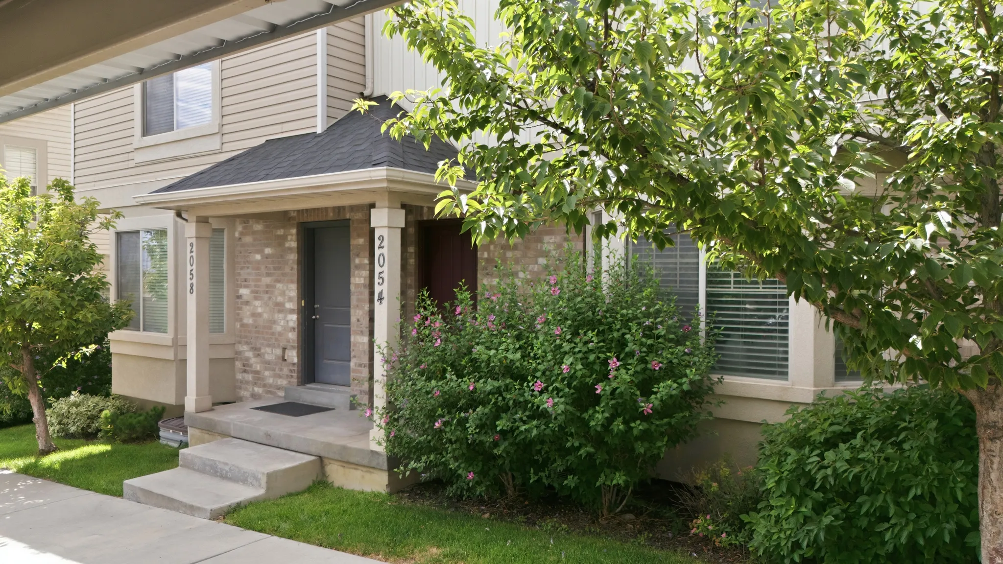 Brick and siding exterior featuring a covered entryway with decorative pillars