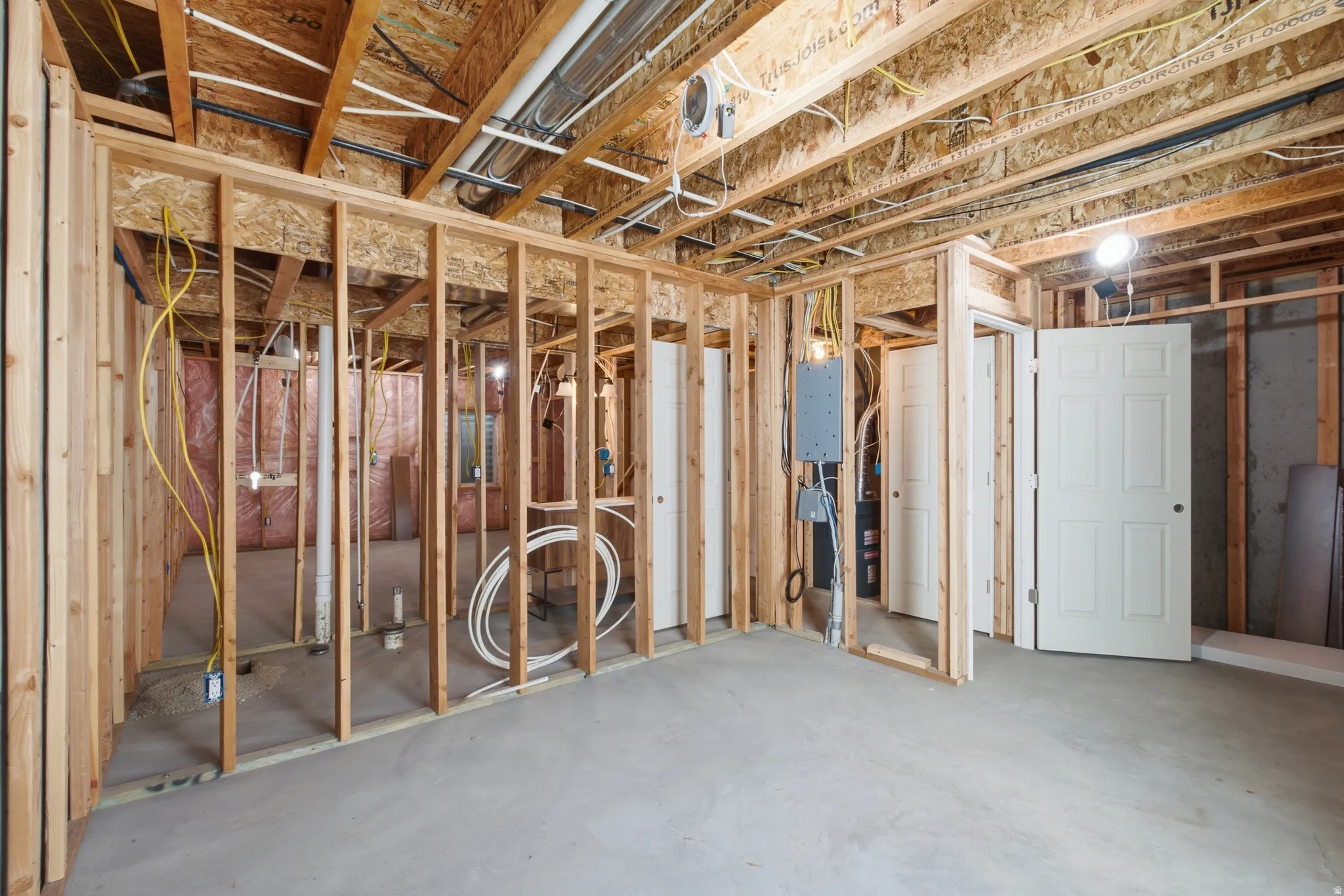 Unfinished basement space featuring visible wood framing, concrete flooring, and exposed ceiling joists