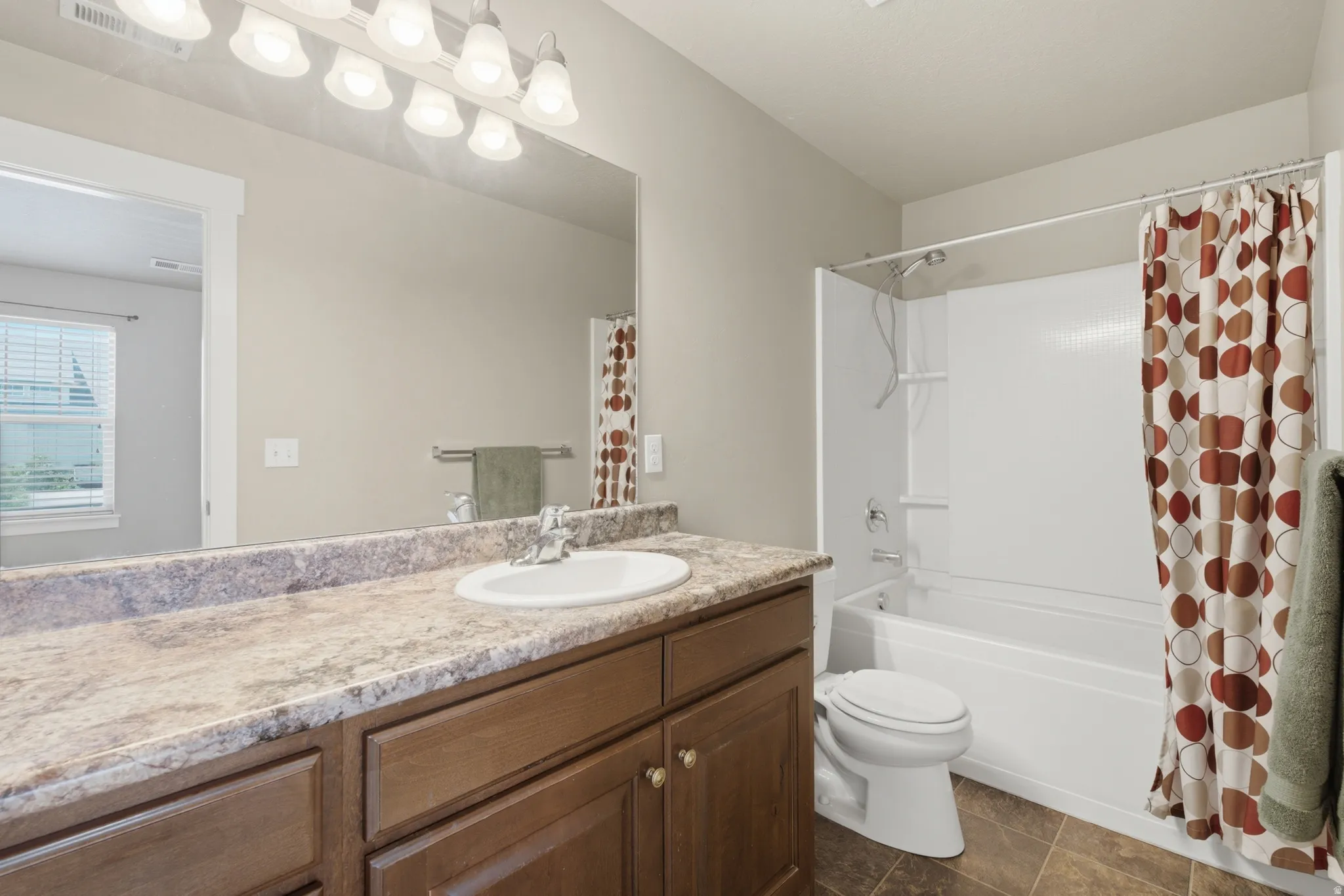 Bathroom featuring a vanity with a laminate countertop, integrated sink, and wood-finish cabinetry