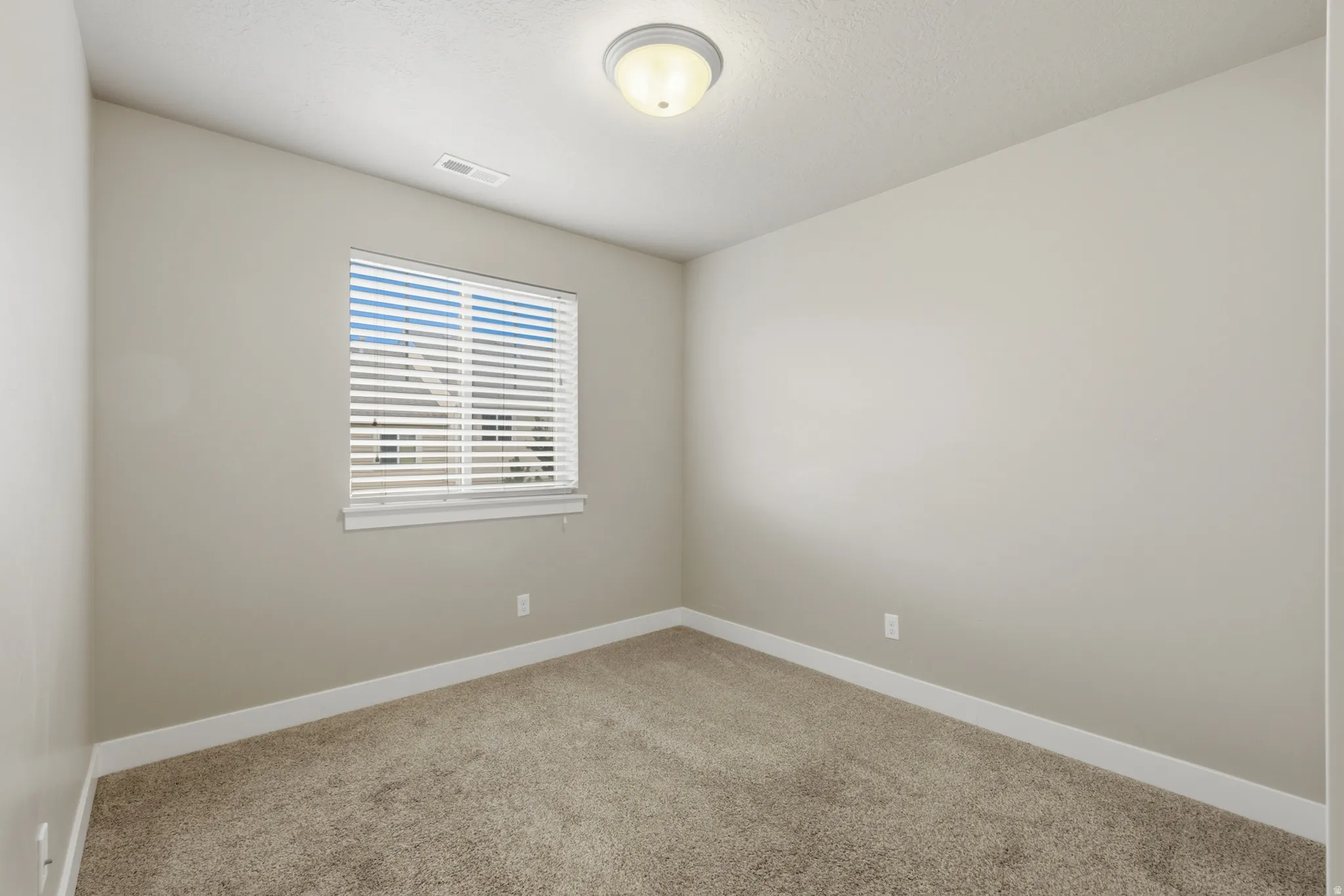 Room featuring neutral-toned walls, white trim, and a window with blinds