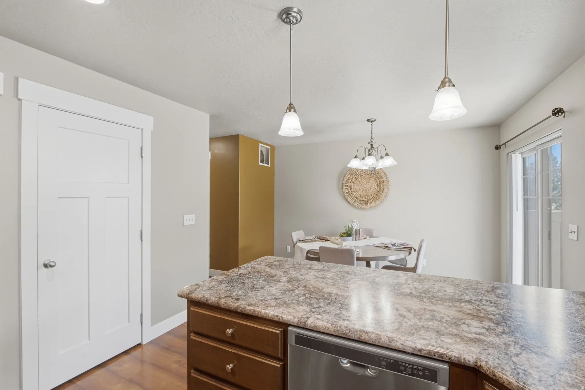 Kitchen island with a light-toned countertop, wood-finish cabinetry, and stainless steel dishwasher