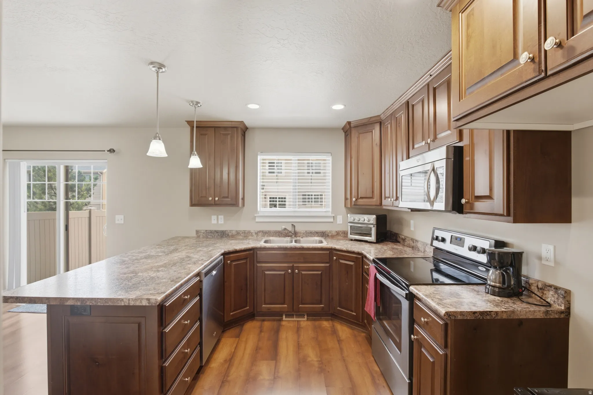 Kitchen featuring extensive U-shaped countertops, wood-finish flooring, and ample cabinetry