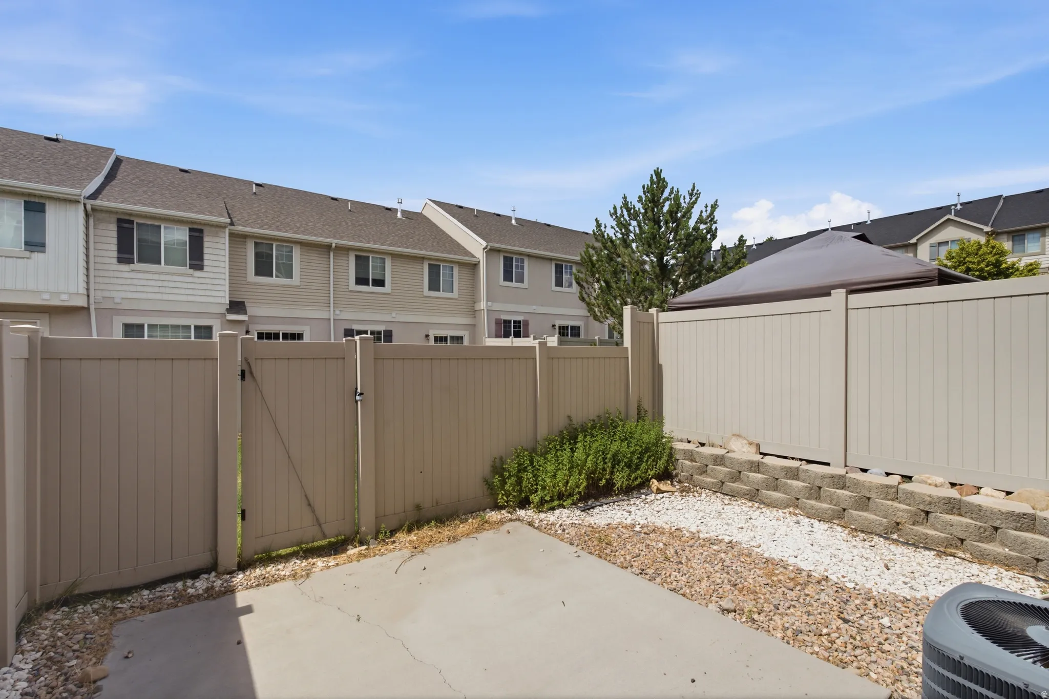 Enclosed courtyard featuring concrete paving, decorative gravel, and a retaining wall, bordered by a privacy fence with a gate
