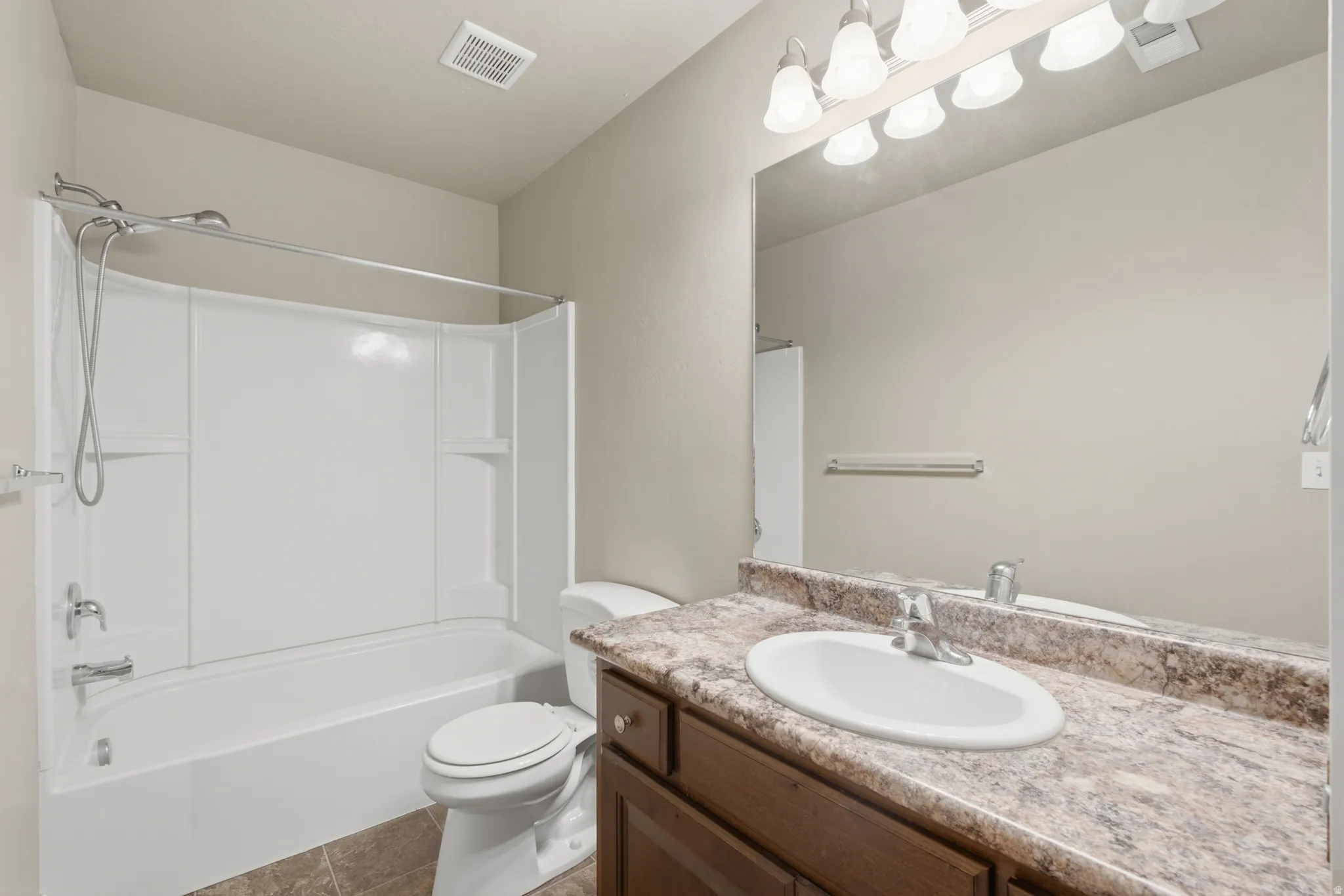 Bathroom featuring a combined tub and shower unit, a vanity with a laminate countertop, and a large mirror