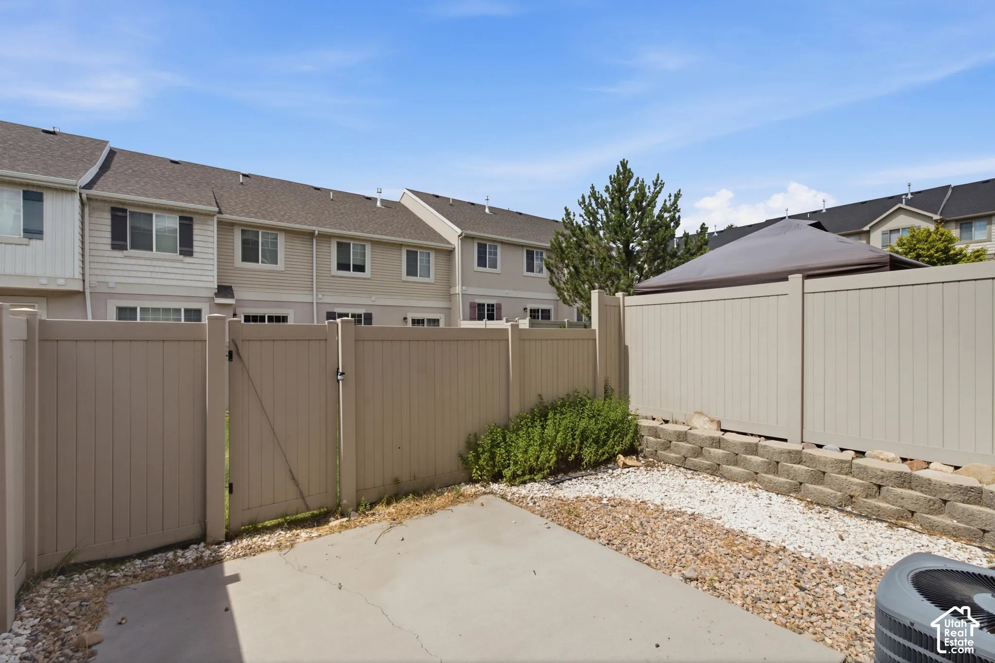 Enclosed courtyard featuring concrete paving, decorative gravel, and a retaining wall, bordered by a privacy fence with a gate