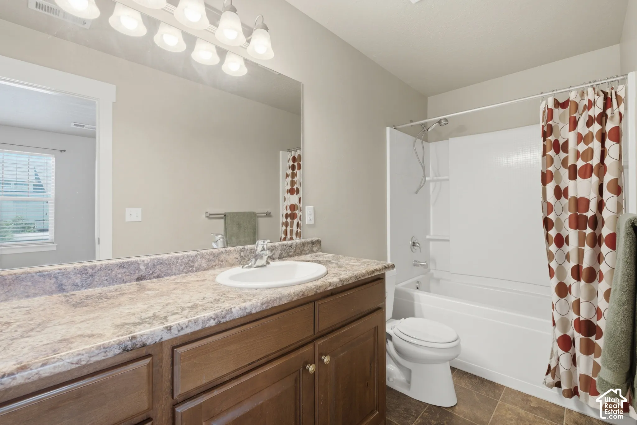 Bathroom featuring a vanity with a laminate countertop, integrated sink, and wood-finish cabinetry