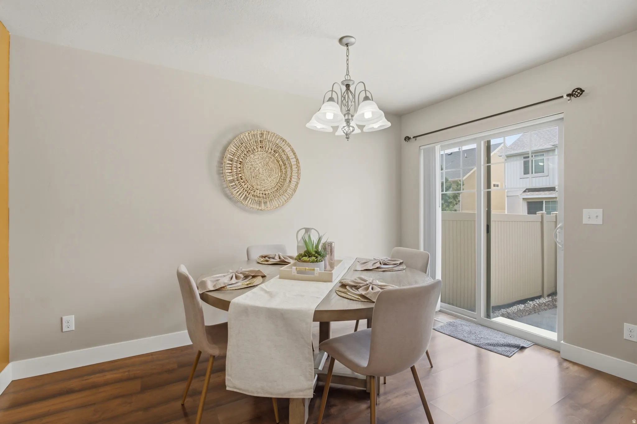Dining area featuring wood-finish flooring, a contemporary chandelier, and a sliding glass door opening to a private outdoor space