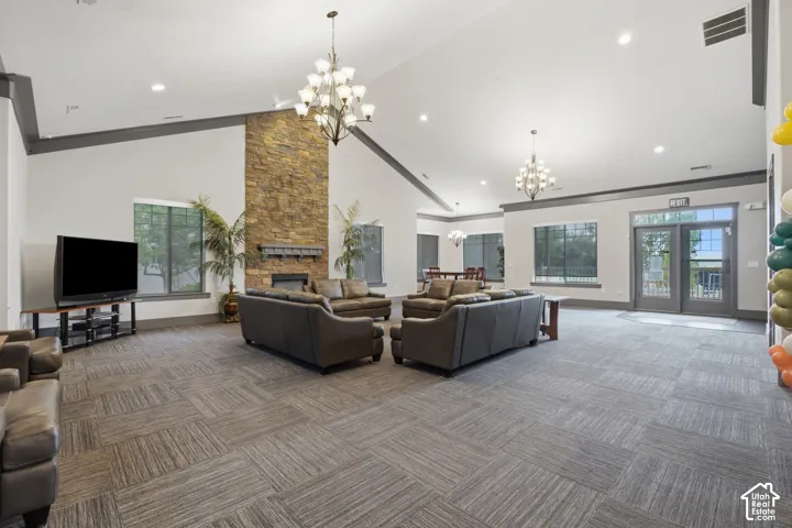 Spacious common area featuring a stone-clad fireplace, vaulted ceilings, and large windows