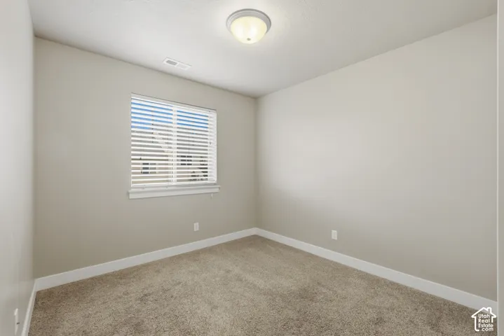Room featuring neutral-toned walls, white trim, and a window with blinds