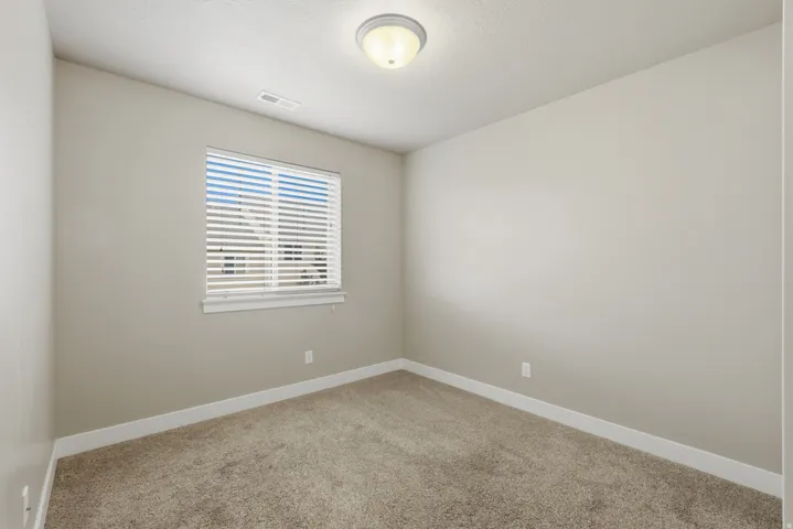 Room featuring neutral-toned walls, white trim, and a window with blinds