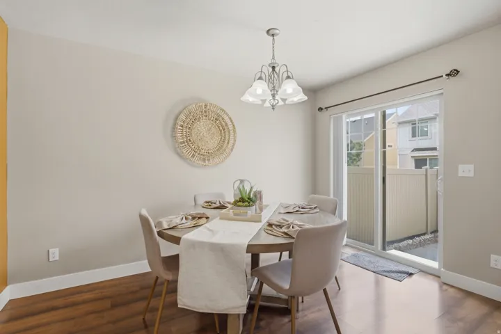 Dining area featuring wood-finish flooring, a contemporary chandelier, and a sliding glass door opening to a private outdoor space