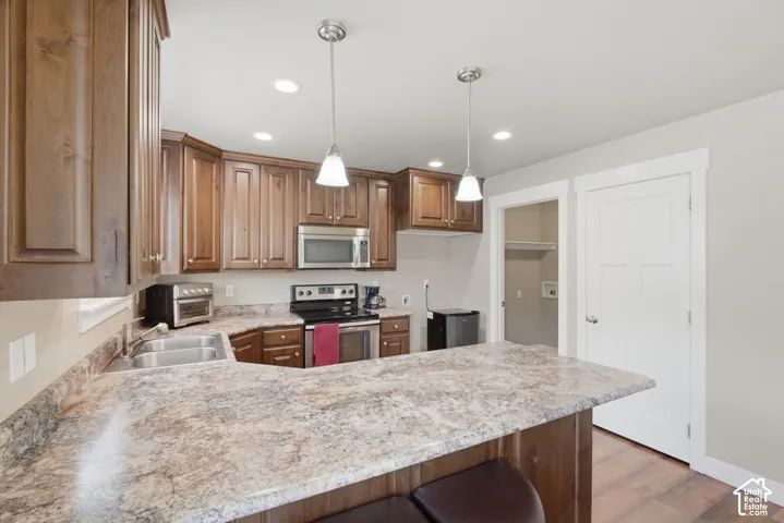 Kitchen featuring wood cabinetry, stainless steel appliances, a double basin sink, and pendant lighting