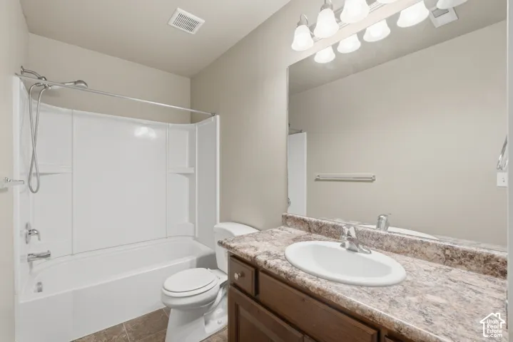 Bathroom featuring a combined tub and shower unit, a vanity with a laminate countertop, and a large mirror