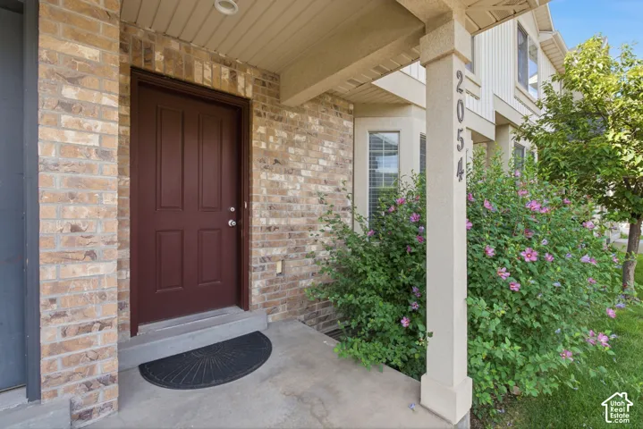 Brick exterior facade featuring a paneled entry door, concrete porch, and bay windows