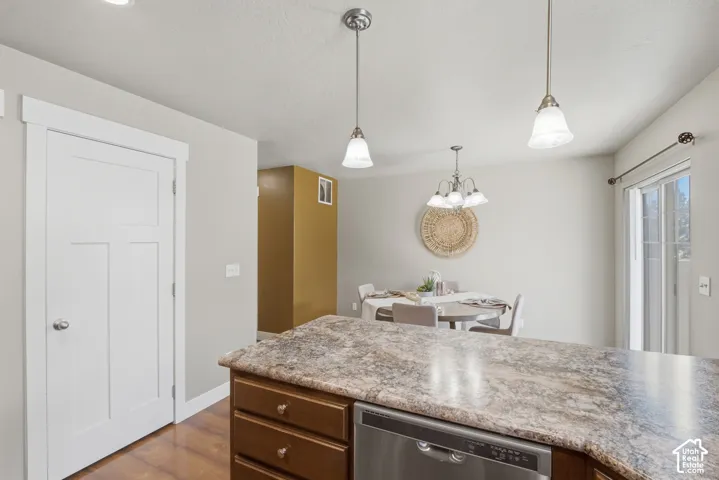 Kitchen island with a light-toned countertop, wood-finish cabinetry, and stainless steel dishwasher
