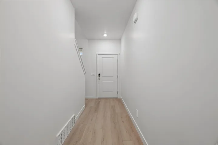Entryway corridor featuring light wood-finish flooring and bright white walls