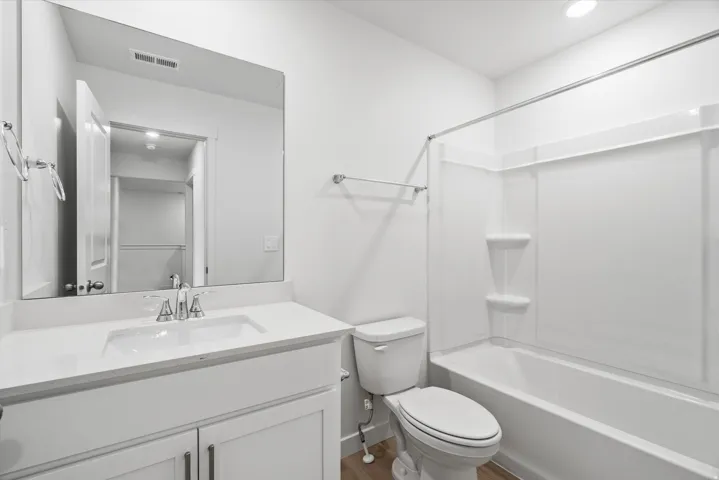 Bathroom featuring a white vanity with an integrated sink, polished chrome faucet, and a large unframed mirror