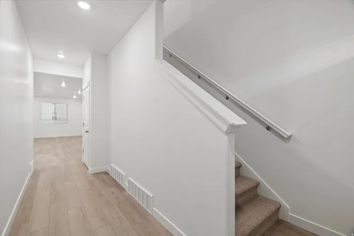 Hallway featuring wood-finish flooring, recessed lighting, and white baseboards
