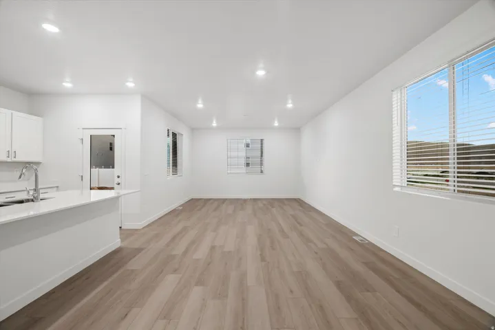 Open-concept living space featuring wood-finish flooring, recessed lighting, and expansive windows with blinds