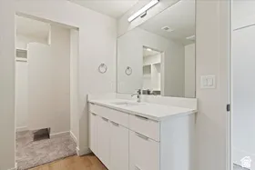 Bathroom vanity with a white countertop and integrated sink, chrome faucet, and expansive wall mirror