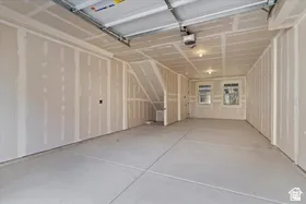 Spacious unfinished garage featuring two windows, recessed lighting, concrete flooring, and an integrated stairway