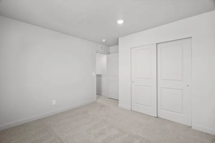 Spacious bedroom with neutral wall finishes, recessed ceiling lighting, and dual closets featuring six-panel doors