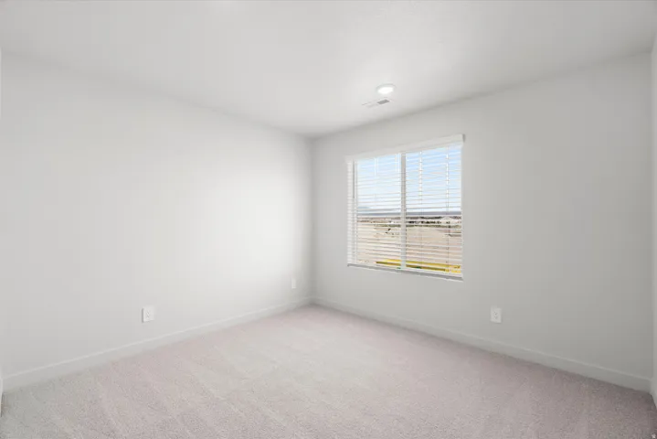 Neutral-toned carpeting, white walls, recessed lighting, and a window with horizontal blinds