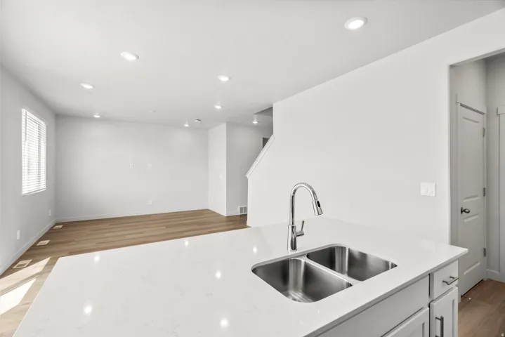 Modern kitchen featuring stainless steel dual-basin sink with chrome pull-down faucet, white quartz countertops, soft-close cabinetry, and recessed ceiling lighting