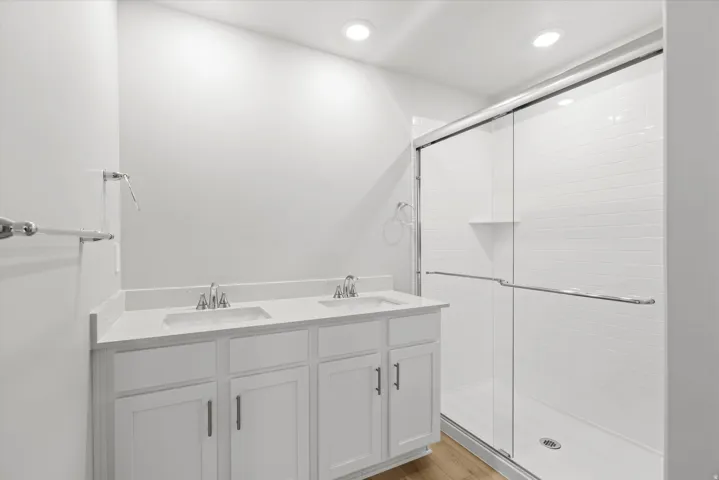 Modern primary bathroom featuring a dual-sink vanity with white cabinetry, chrome hardware, and a white quartz countertop