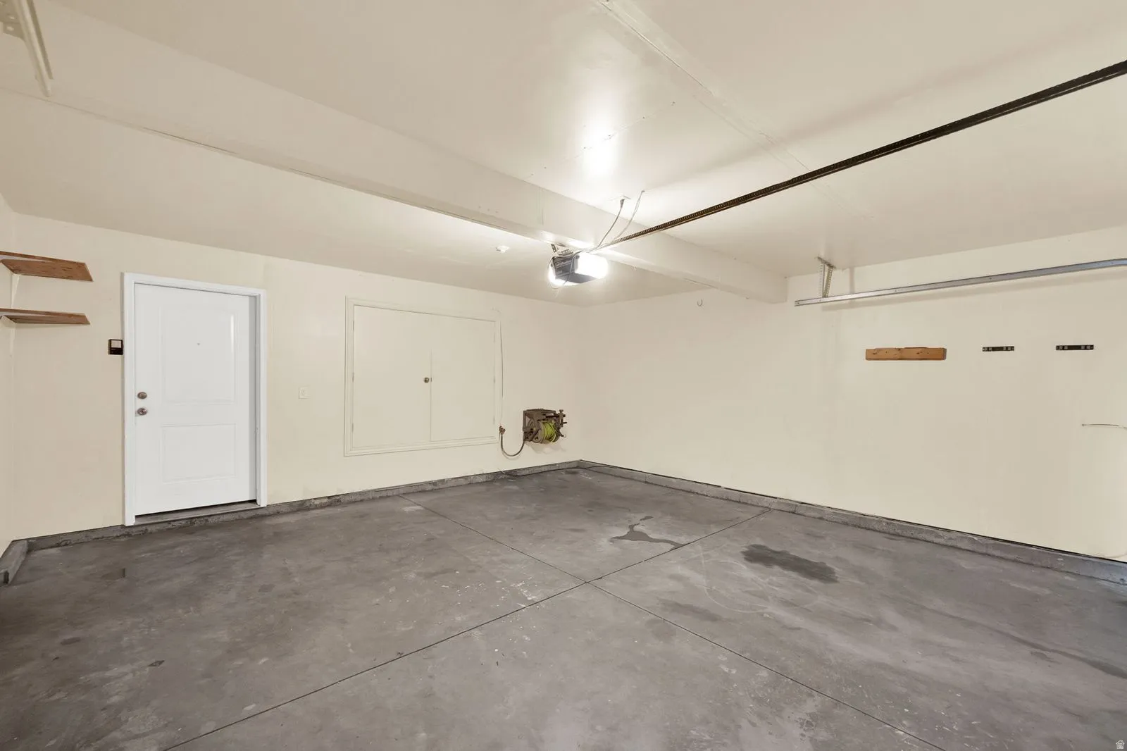 Spacious garage featuring a concrete floor, painted walls, overhead lighting, and built-in shelving