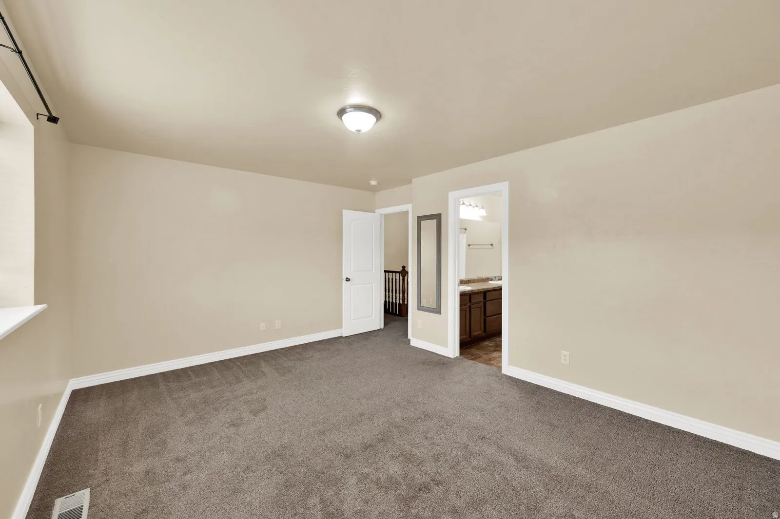 Spacious room featuring neutral carpeting, light-toned wall paint, and white trim