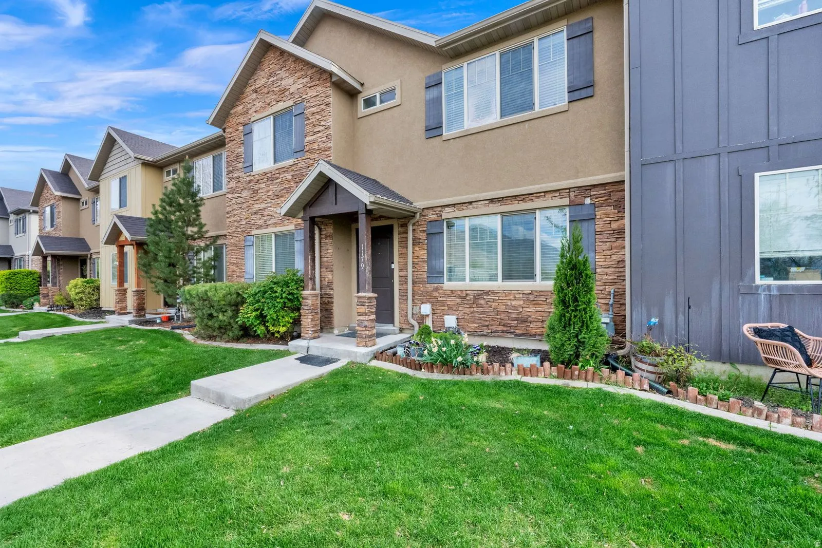 Townhome exterior featuring a combination of stone veneer and stucco siding