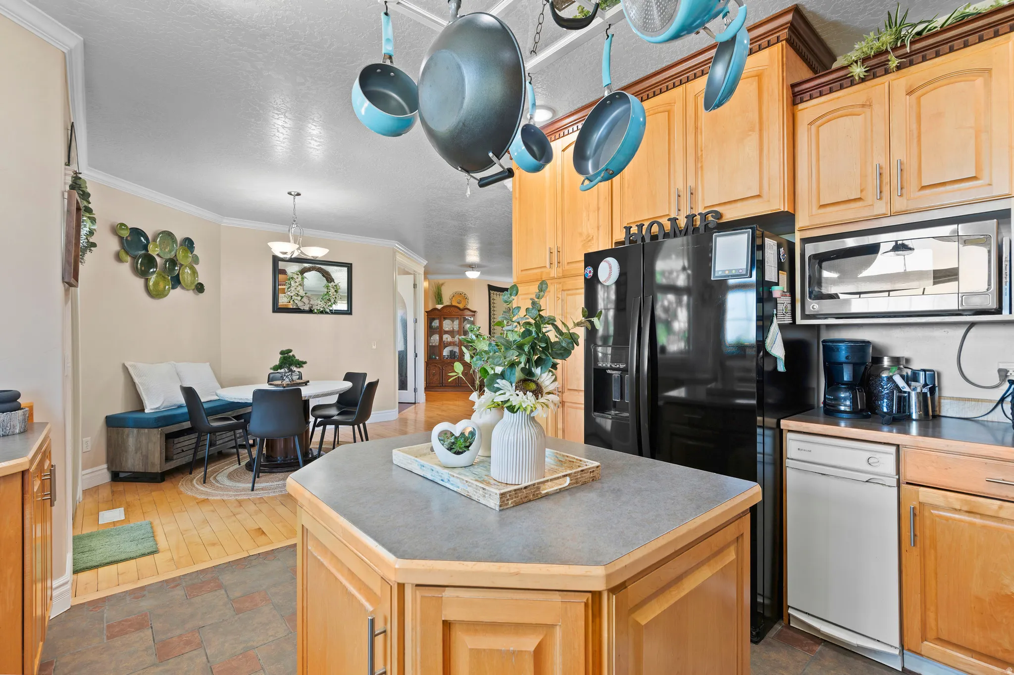 Kitchen featuring a functional island, natural wood cabinetry, a black refrigerator, and a built-in microwave