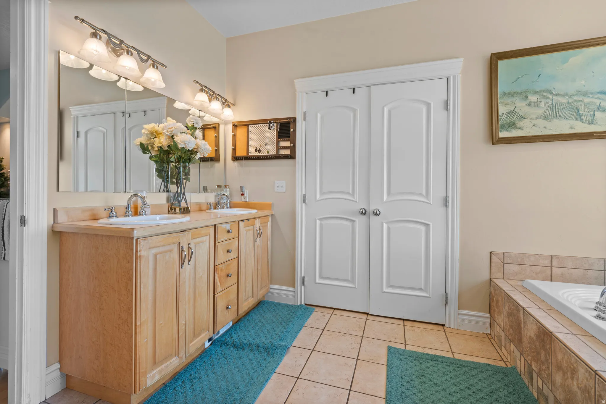 Dual vanity with light wood cabinetry, white sinks, and brushed nickel fixtures