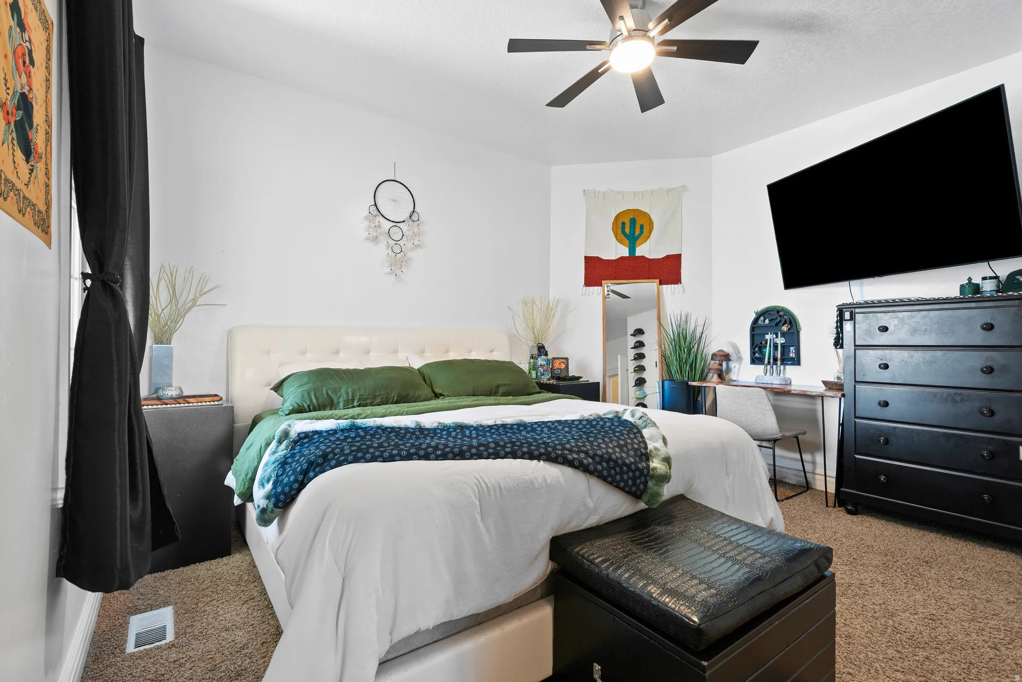 Bedroom featuring a built-in ceiling fan, white wall finishes, and textured carpet flooring