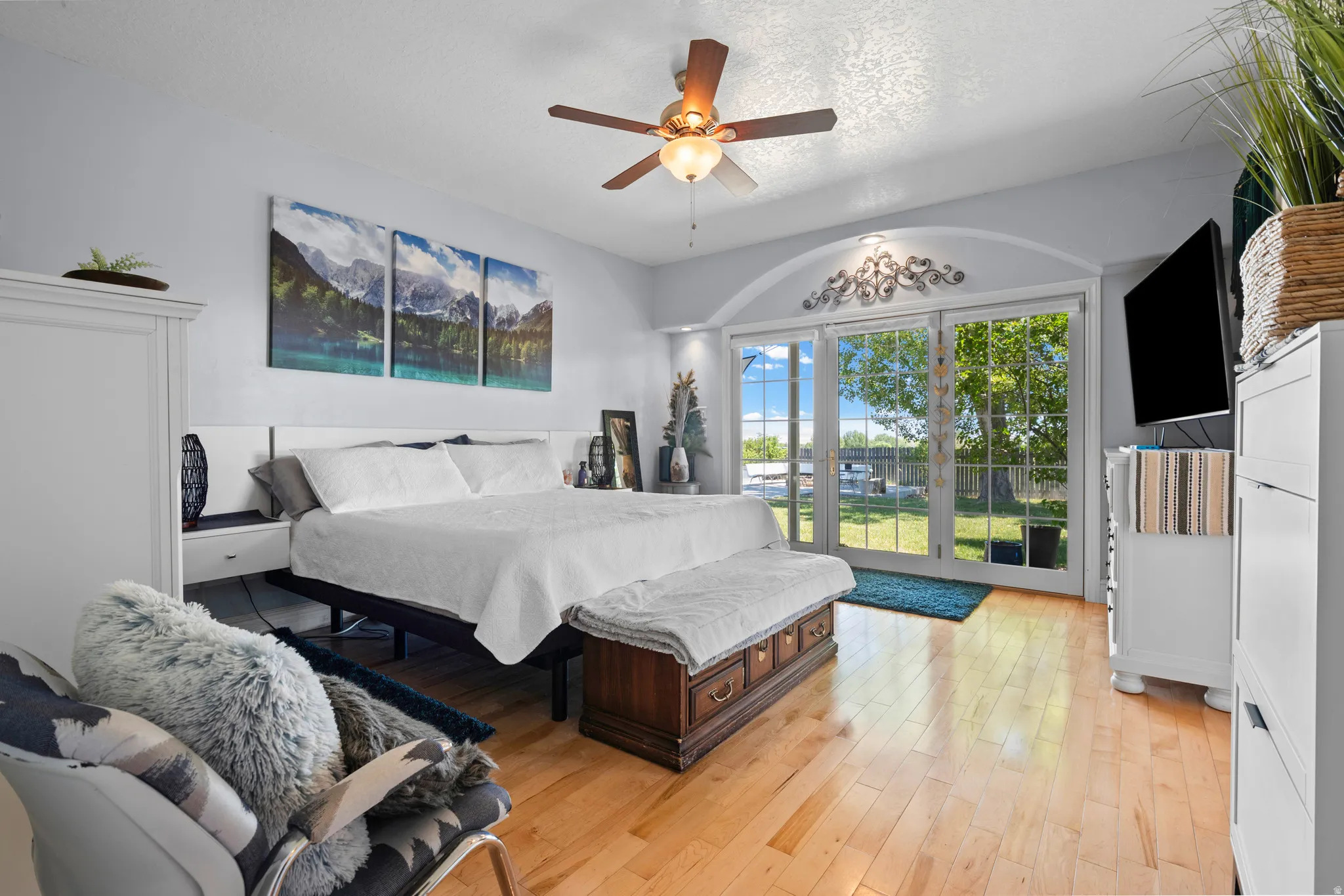 Hardwood flooring complements the bright interior featuring a ceiling fan and direct outdoor access through French doors